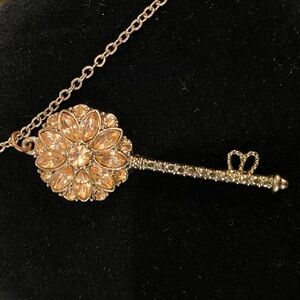Flower key pendant on a 36 inch silver tone necklace